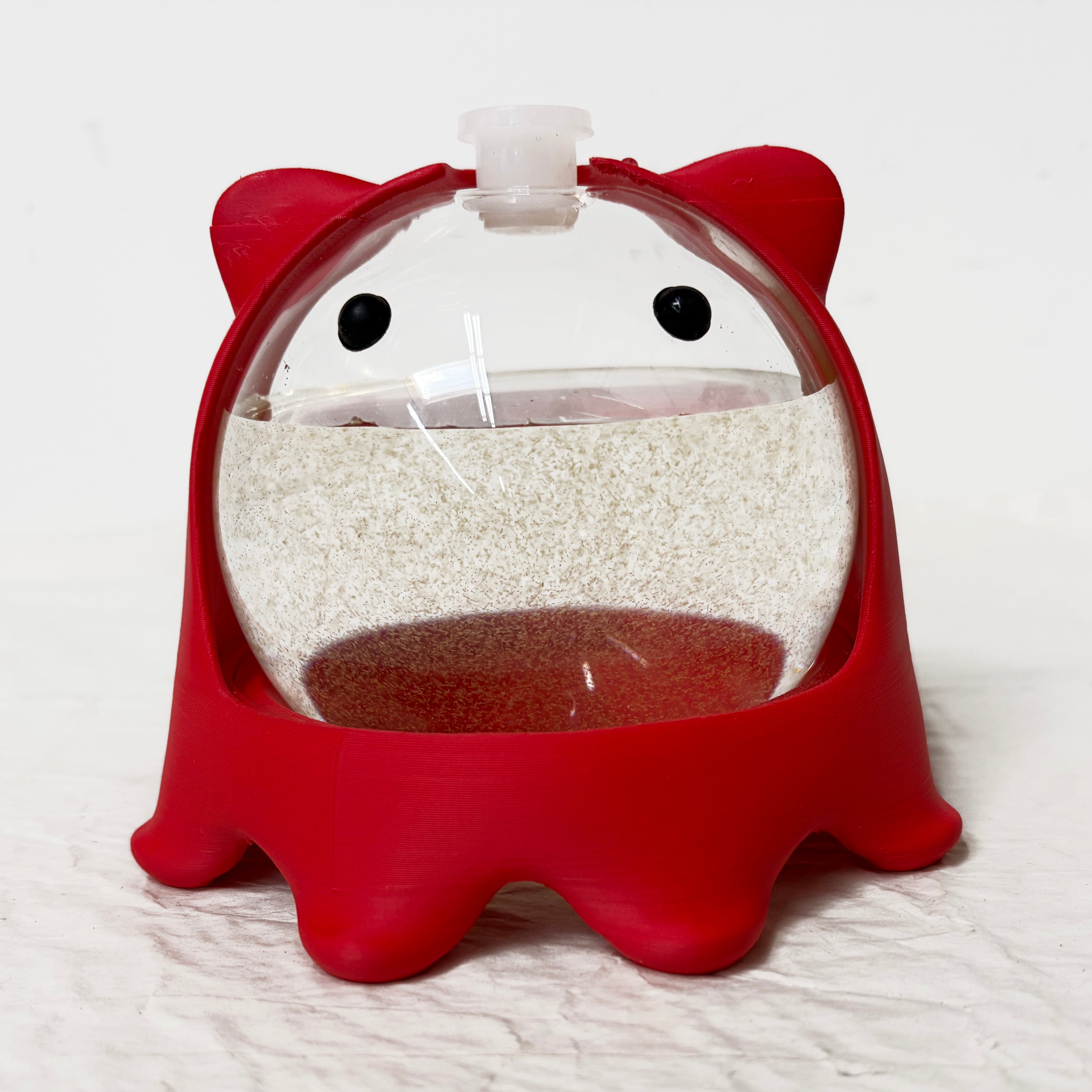 PyroPet bioluminescent plankton orb in red 3D-printed stand during daytime with PyroDinos culture inside