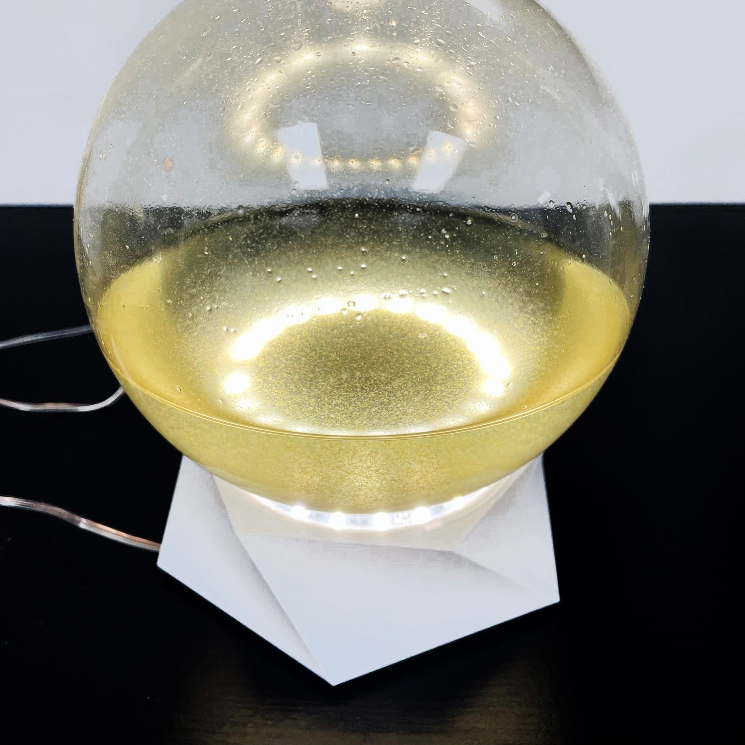 A bioluminescent glass bio-orb representing a micro-aquarium with living algae.
