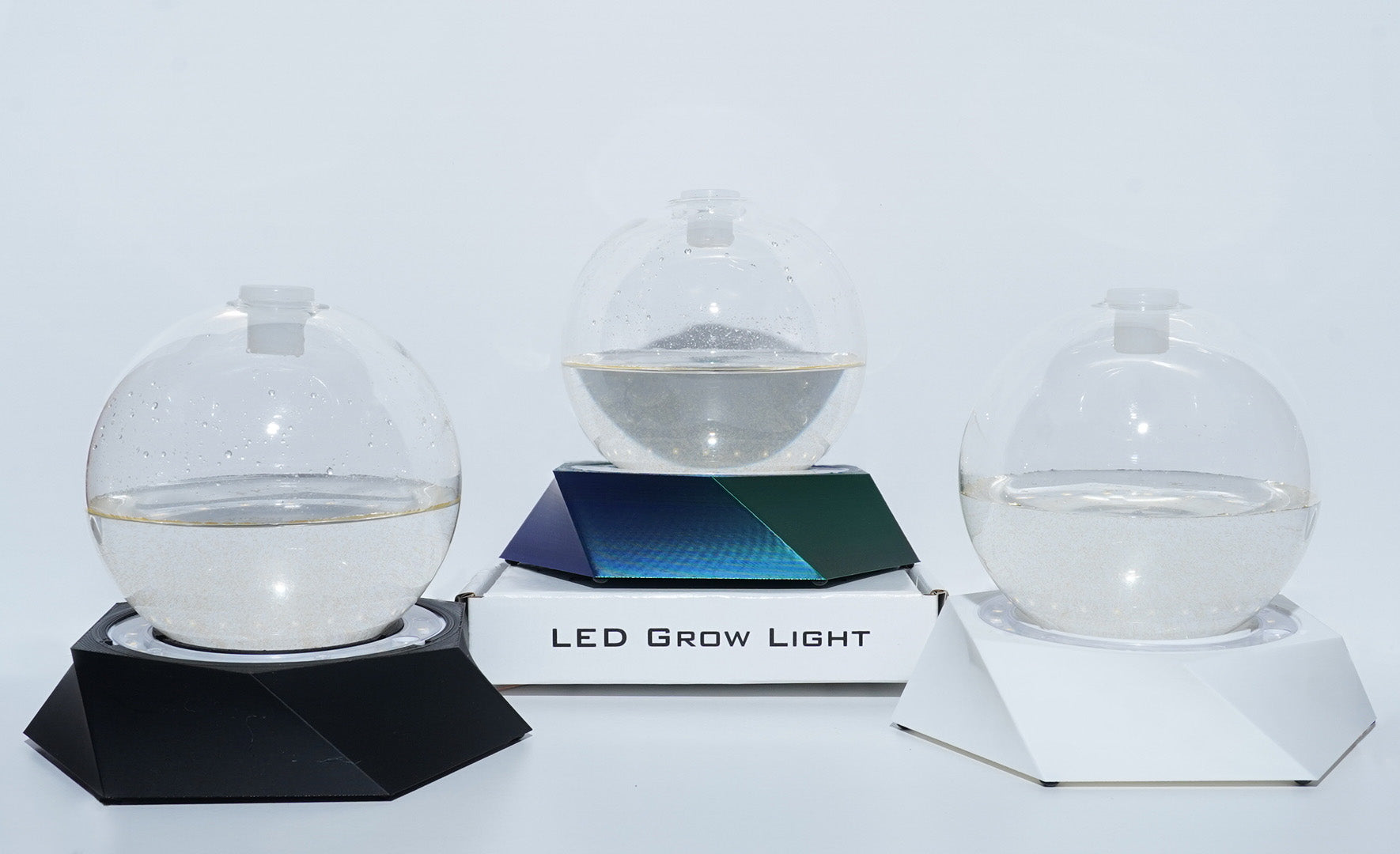 Three PyroDino LED grow light stands illuminating three Bioluminescent Bio-Orb