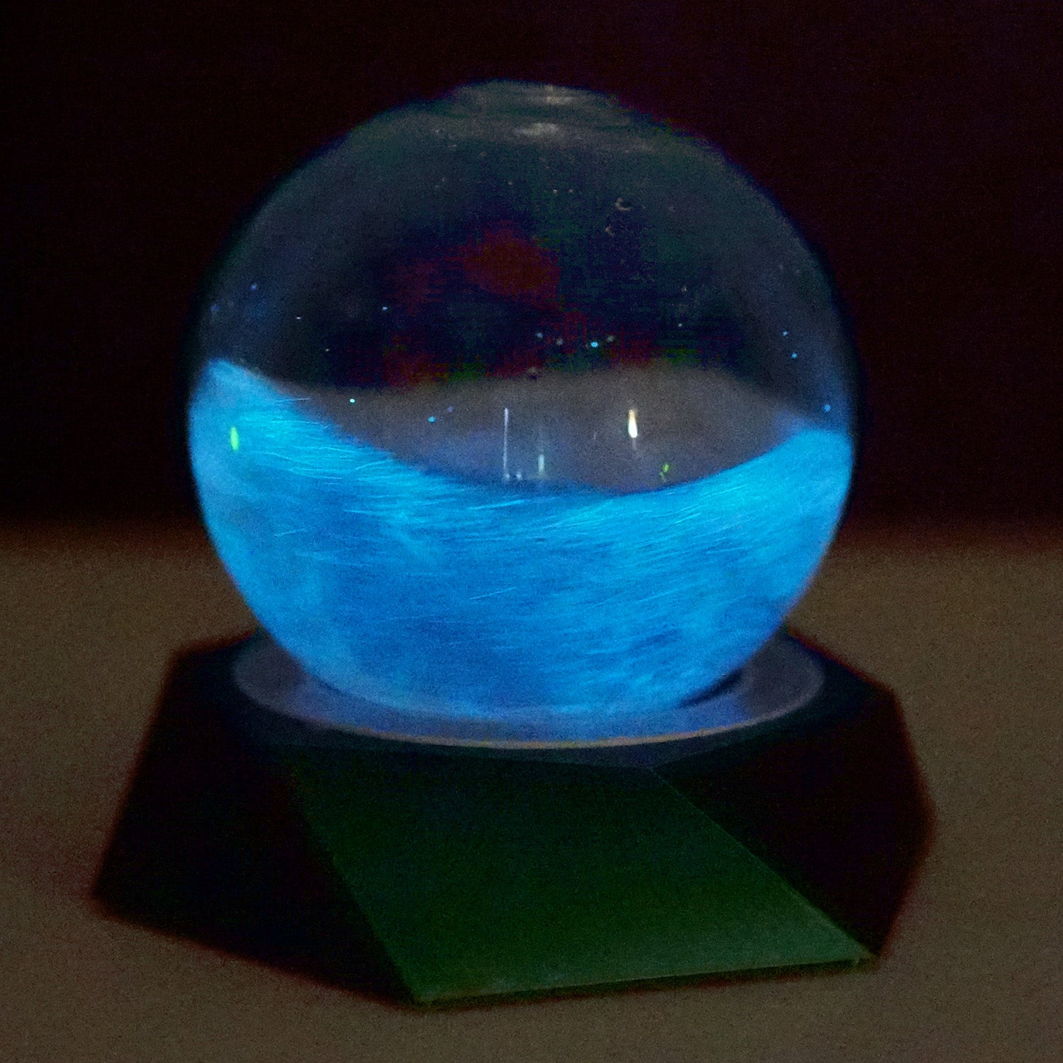 Glowing PyroDino Bio-Orb on the programmable LED grow light in a dark room setup